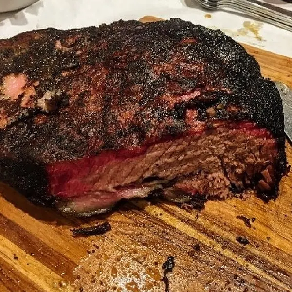 Smoked brisket with a dark bark, sliced to show the smoke ring